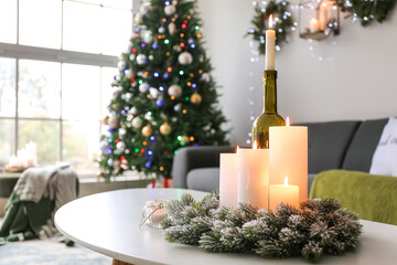 Burning candles in interior of living room decorated for Christmas