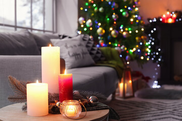 Burning candles in living room decorated for Christmas