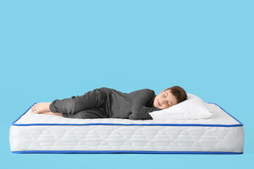 Cute little boy sleeping on mattress against color background