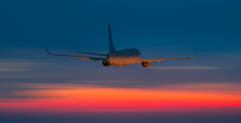 Fototapeta na wymiar Airplane in the sky at amazing red sunset