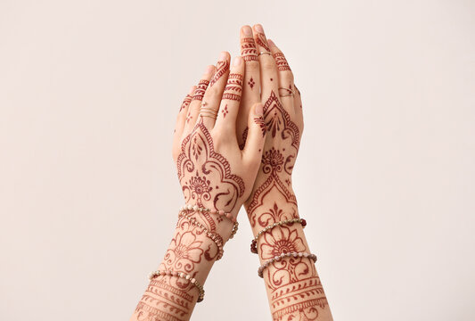 Beautiful female hands with henna tattoo on light background