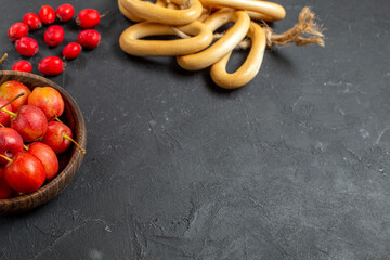 Fresh red cherries inside a brown bowl and cookies on dark background