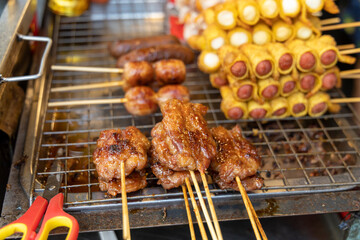 Thai street food, skewers with wrapped sausages, Issan sausages and Moo Ping, coconut grilled pork