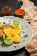 Vertical view of homemade cutlet meal along with potatoes and different spices next to towel