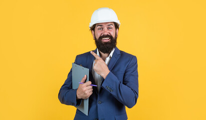 man with beard and moustache in helmet look as businessman on construction site, boss pointing finger