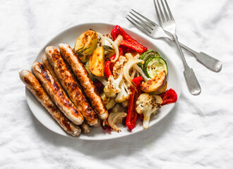 Grilled turkey sausages and roasted vegetables on a light background, top view. Delicious lunch, tapas, appetizer