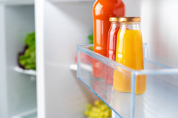 Glass bottle of juice on a fridge shelf