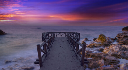 Wooden pier or jetty on a sea at amazing sunset