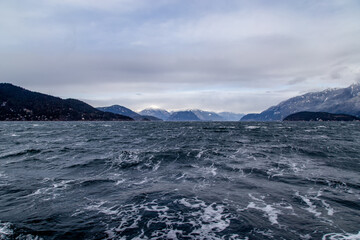 snow covered mountains in rough, winter weather on Howe Sound on a stormy ferry ride to Bowen Island, BC Canada