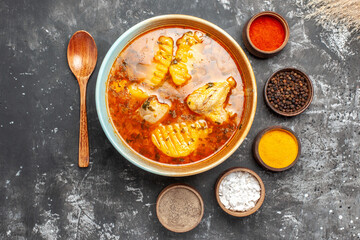 Overhead view of chicken dish spices set and spoon on dark background