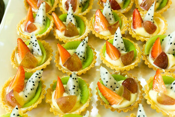 Fototapeta na wymiar Fresh fruit pie tarts dessert tray assorted top view background. Beautiful delicious tarts, colorful pastry cakes sweets with fresh dragon fruits, grapes, strawberry, kiwi. French Bakery pattern.