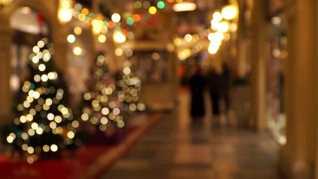 Department store with christmas golden decorations in defocus. Bokeh background of blurred decorated shopping center with people shopping on christmas and new year's eve.