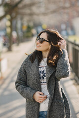 Obraz premium Elegant girl walk in a winter city. Woman in a white knited sweater. Beautiful lady with dark hair.