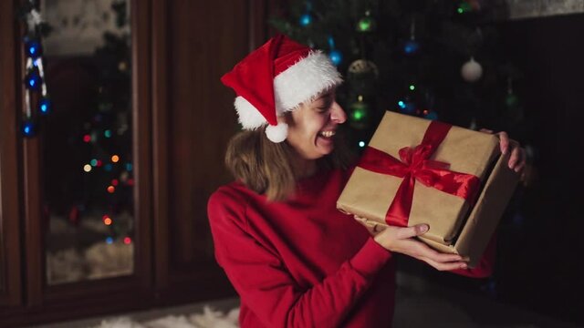 girl in red clothes unfold New year gifts. the concept of celebrating Christmas midnight. Holiday's decor boce, Christmas tree