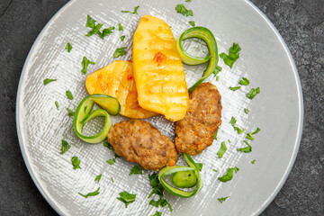 Close up view of tasty dinner with cutlet meal potatoes on a white plate on dark table