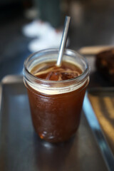 Close up glass of iced black Americano coffee on metal tray with stainless steel straw