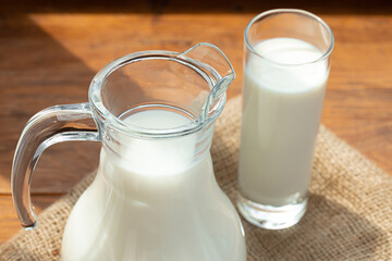 Glass pitcher of milk on old wooden table