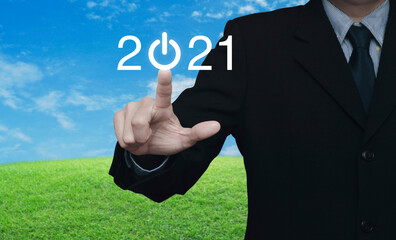 Businessman pressing 2021 start up business flat icon over green grass field with blue sky, Business happy new year cover concept