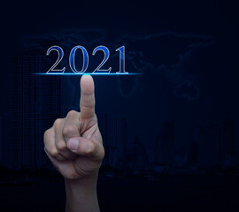 Hand pressing 2021 text over world map, modern office city tower and skyscraper, Business happy new year 2021 cover concept, Elements of this image furnished by NASA