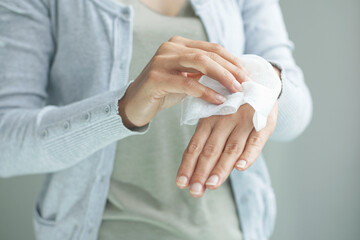 Woman cleaning her hands by using white tissue paper. isolated on a gray background.