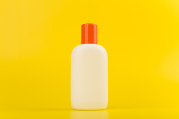 Unbranded sunscreen cream on bright yellow background. Minimalistic still life with a space for text