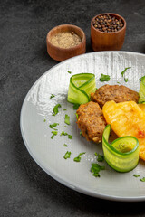 Homemade cutlet meal along with potatoes and different spices on dark background