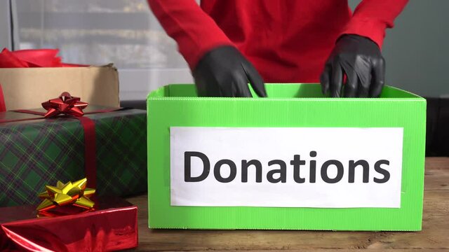 Donation box, fundraising, sponsorship in Christmas. A volunteer in gloves. Giving to others during the holiday season by donating to a charity that provides gifts for needy children