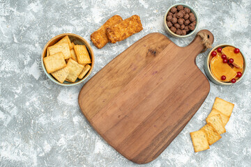 Delicious biscuits and cakes for breakfast and cutting board on blue background