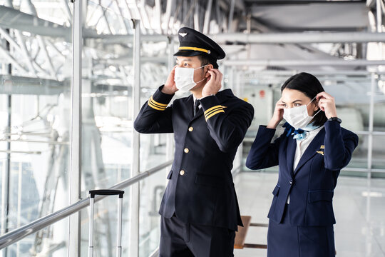 Asian young pilot and flight attendant put on face mask in the airport