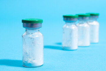 A jar of antibiotic powder on a blue background. Manufacturing drugs in pharmacology, pharmaceuticals and pharmacy. Copy space for labeling in the pharmacological medical industry