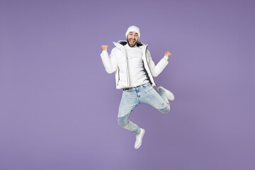 Full length happy man in warm white padded windbreaker jacket hat jumping doing winner gesture...