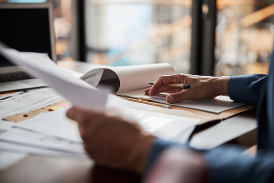 Skillful editor working with paperwork at his office - Powered by Adobe