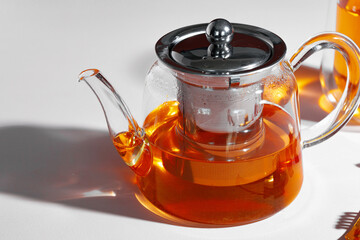 Glass teapot with fruit tea on table background