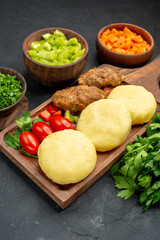 Top shop of dinner background with tasty cutlets vegetables and greens on dark background