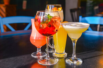 Cocktails on the table. Different coloured drinks in different glasses on dark wooden table.