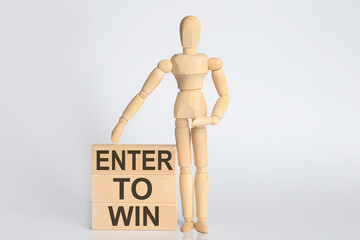 Wooden man shows with a hand text ENTER TO WIN concept on the wooden block