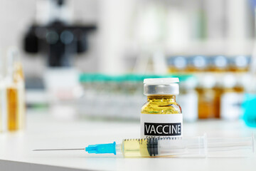 Vaccine in vial for injection on table against background of laboratory