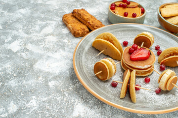 Top view of homemade pancake decoration and biscuits on a white plate and white background