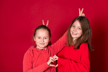 best girlfriends wearing red clothes posing and standing in front of red background