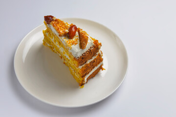 Closeup of one piece pumpkin layer cake with caramel and nut topping. Seasonal autumn cake with caramel syrup.