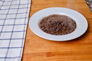 White plate with black beans on a wooden board