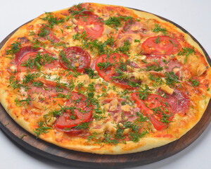 Pizza pollo with chicken meat, tomatoes and ham served on a round wooden board over white background.