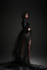 Fototapeta na wymiar fashion portrait of elegant sexy brunette woman in long black dress on studio background