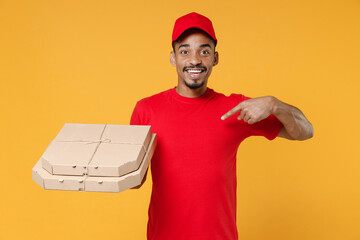 Delivery employee african man 20s in red cap blank print t-shirt uniform workwear work courier dealer service concept hold give food order pizza cardboard boxes isolated on yellow background studio.