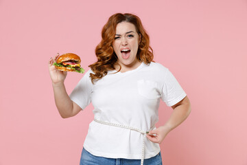 Irritated young redhead plus size body positive woman 20s in white casual t-shirt hold american...