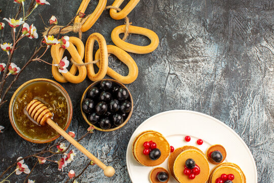Top view of fruit pancakes near honey in a bowl and black cherries with cookies stock image