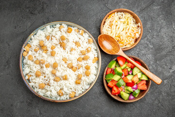Overhead view of seasoned split peas and rice sauerkraut and salad on dark background