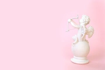 figurine of an angel Cupid with a bow on a pink background. Valentine's Day.
