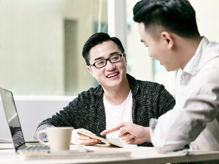 Obraz premium two asian entrepreneurs discussing business in office