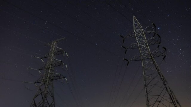 High voltage electric tower on milky way sky background, High voltage electricity pylon and transmission power line and power line insulators at night with Geminids Meteor Shower.